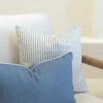 2 outdoor sofa cushions in a pacific blue colour arranged in the corner of a white sofa.