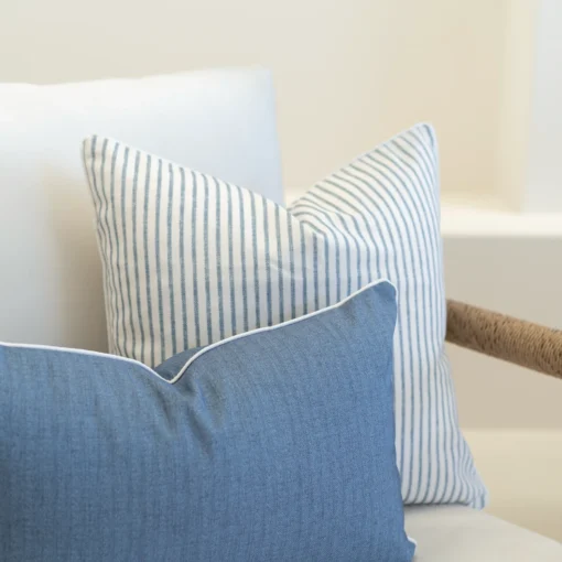 2 outdoor sofa cushions in a pacific blue colour arranged in the corner of a white sofa.