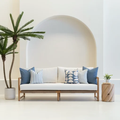 A set of 5 pacific blue outdoor cushions sitting on a wooden sofa in an airy white living room.