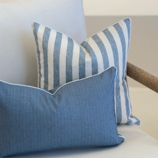 A set of 2 pacific cove outdoor cushions in the corner of a white sofa.