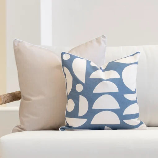 A white sofa with a set of 2 pacific cove outdoor cushions displayed on its corner.