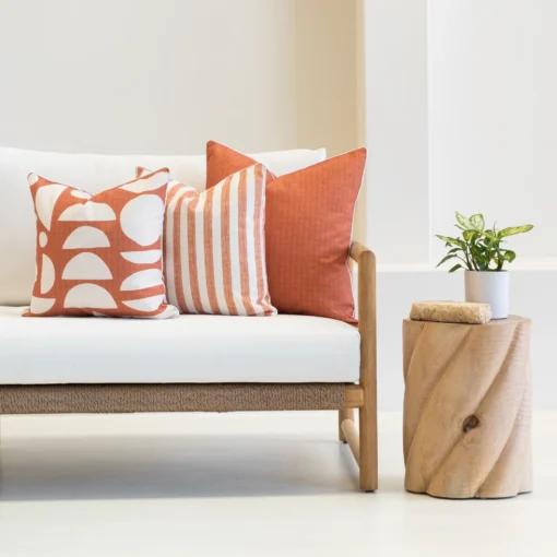 3 pacific rust coloured outdoor sofa cushions are beautifully styled on a white couch.