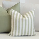 2 pacific outdoor sage cushions tucked on a white sofa.