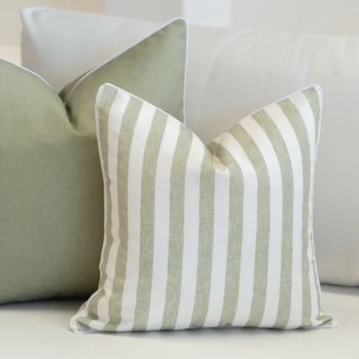 2 pacific outdoor sage cushions tucked on a white sofa.