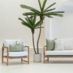 4 pacific sage outdoor cushions are displayed on a white sofa in an outdoor living room.
