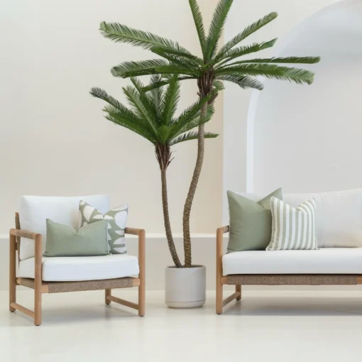 4 pacific sage outdoor cushions are displayed on a white sofa in an outdoor living room.