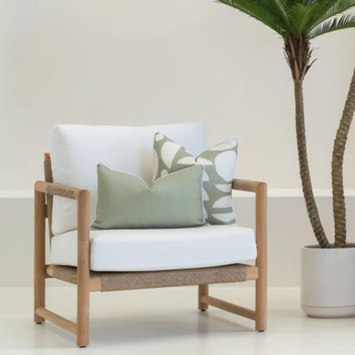 White armchair with 2 outdoor cushions carefully arranged on it.