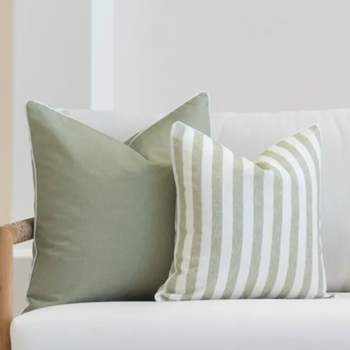 2 outdoor cushions in pacific sage colour displayed on a white sofa's corner.