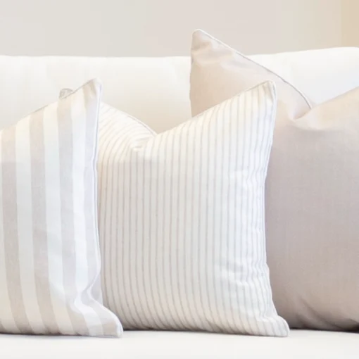 A set of 3 outdoor couch cushions in pacific sand colour are displayed on a white couch.