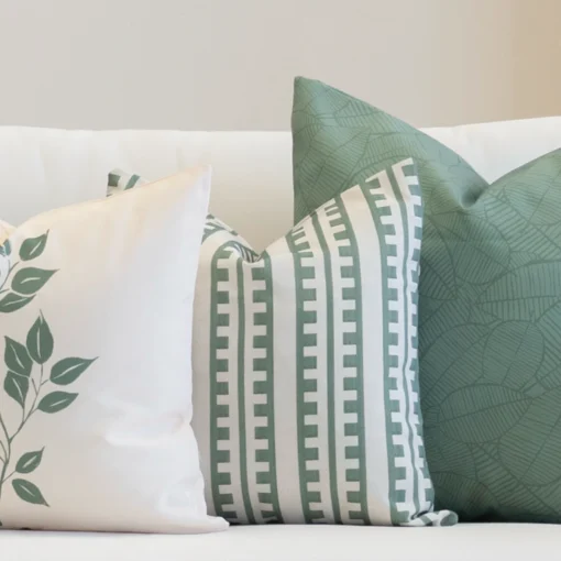 A set of 3 outdoor couch cushions in sagewood colour are displayed on a white couch.