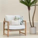 A set of 2 sagewood outdoor cushions sitting on a white armchair.
