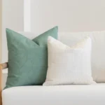 White living room scene with 2 sofa cushions arranged on a sofa.