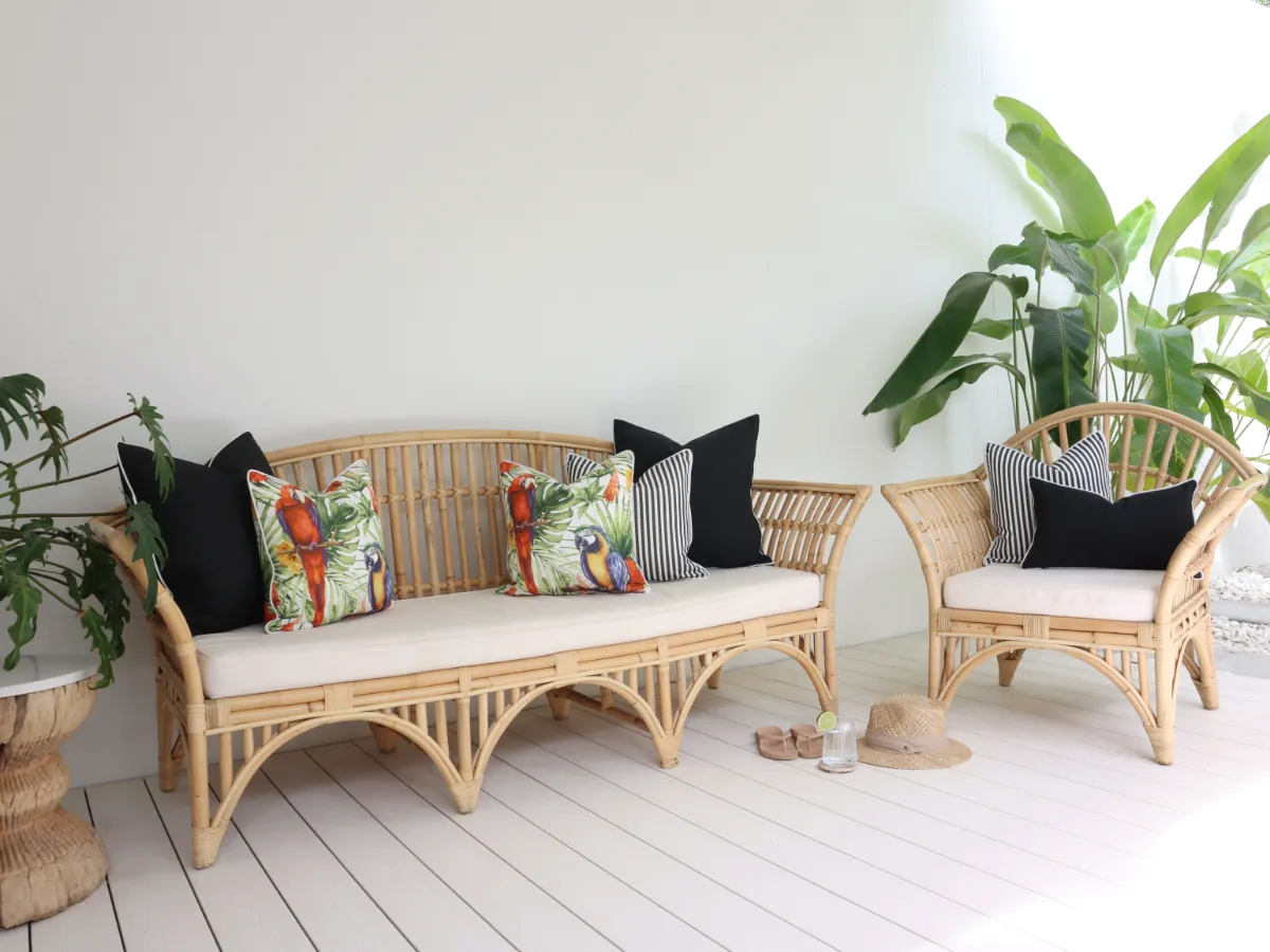 An accent colour palette is being used with black and white outdoor cushions providing the backdrop to a tropical feature cushion used as the accent piece.