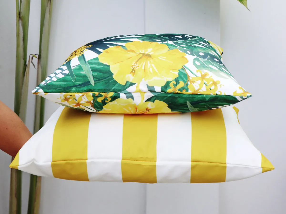A hand is displaying a stack of two yellow outdoor cushions.
