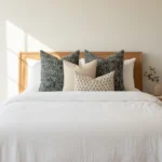 A set of 4 designer cushion covers arranged on a white bed.