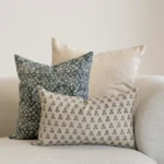 3 designer cushions covers displayed in the corner of a natural coloured sofa.