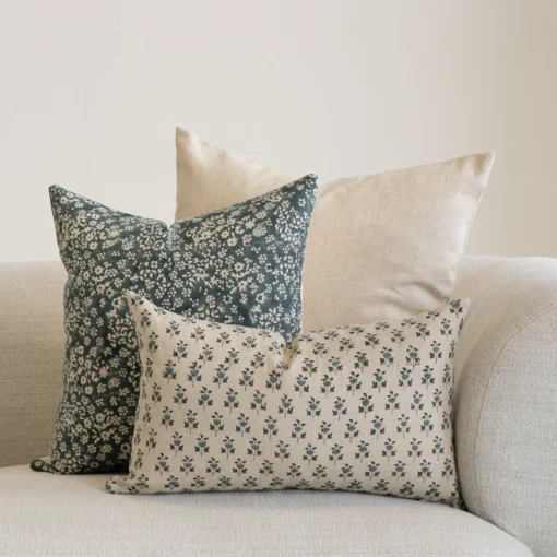 3 designer cushions covers displayed in the corner of a natural coloured sofa.