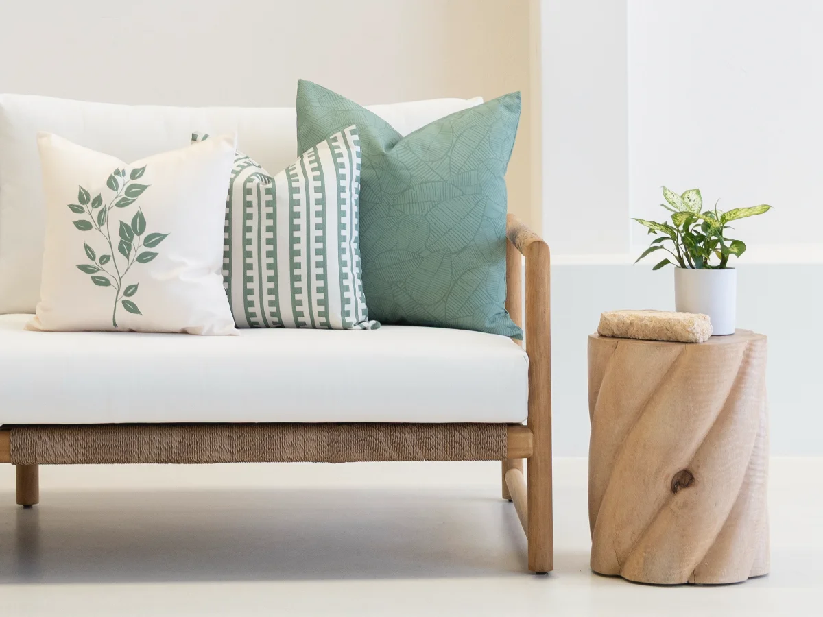 A trio of sage green outdoor cushions on a sofa setting showing a patterned monochrome colour palette.