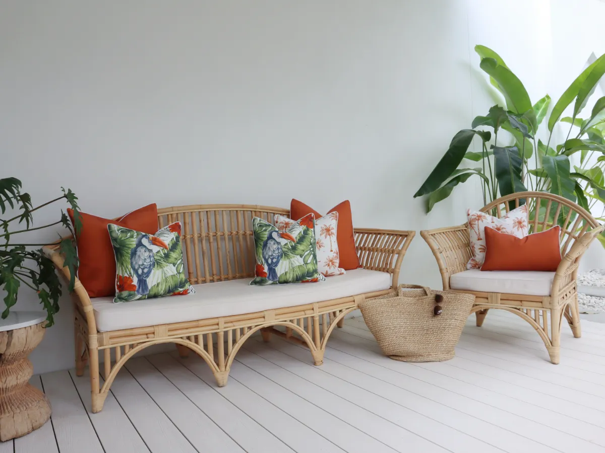 A selection of red outdoor cushions arranged across armchair and sofa furniture.