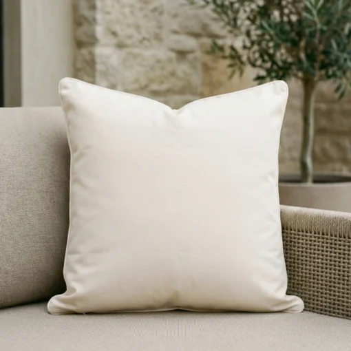 Cream waterproof cushion with white piping on outdoor wicker armchair.