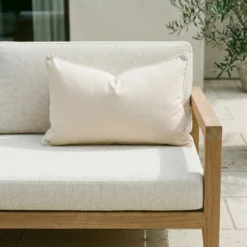 Rectangular cream cushion with white piping on outdoor sofa seat.