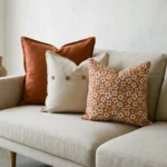 Marenca burnt orange cushions on beige sofa with floral and button detail designs.