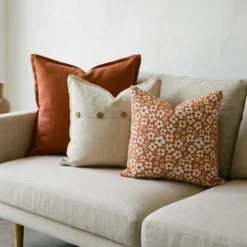 Marenca burnt orange cushions on beige sofa with floral and button detail designs.