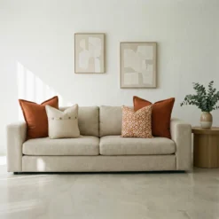 Marenca burnt orange cushions styled on beige sofa with patterned accent cushions.