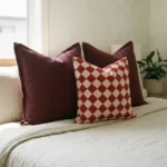 Marenca diamond cushions on bed with burgundy and checkered pattern combination.
