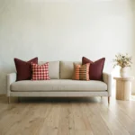 Marenca ginger cushions arranged on beige sofa with red and orange patterns.