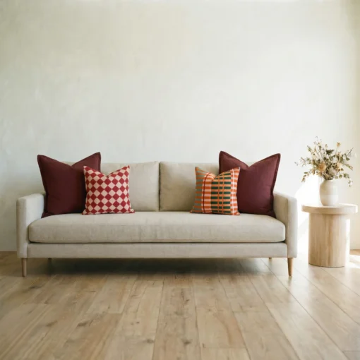 Marenca ginger cushions arranged on beige sofa with red and orange patterns.