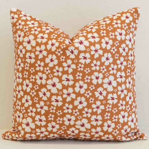 Ditsy floral cushion cover with delicate white blossoms on a warm ochre base for a fresh, inviting look.