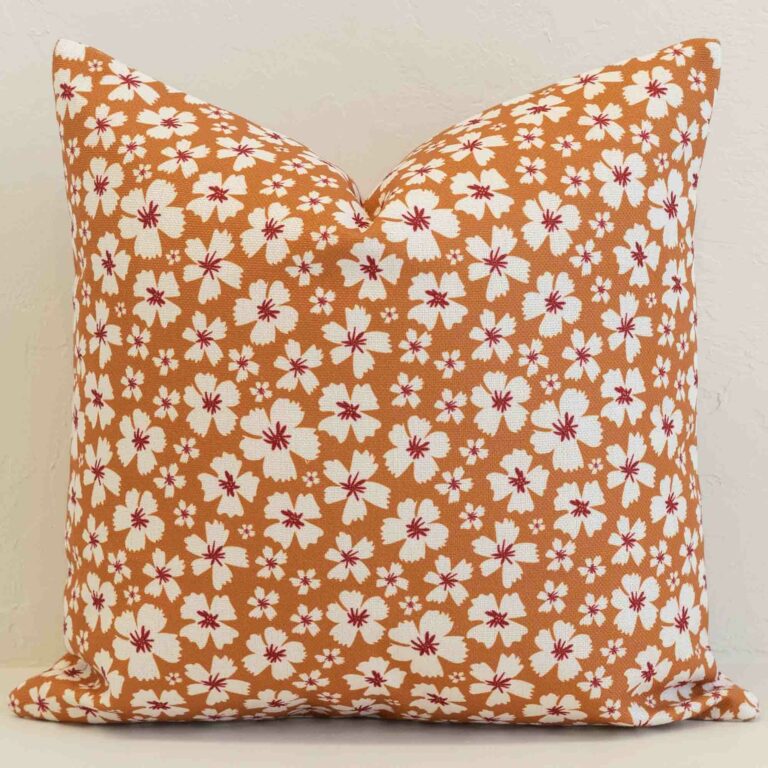 Ditsy floral cushion cover with delicate white blossoms on a warm ochre base for a fresh, inviting look.