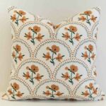 Floral scallop cushion cover with warm ochre blooms set within a soft geometric lattice.