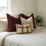 Marenca burnt orange cushions on bed with floral and plaid patterns in warm tones.