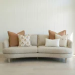 Marenca tan cushions arranged on sofa with neutral tones and soft textured lumbar cushion.