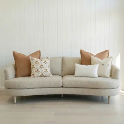 Marenca tan cushions arranged on sofa with neutral tones and soft textured lumbar cushion.