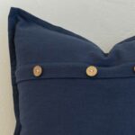 Close-up of navy linen cushion with natural wooden button closure and tailored edge finish.