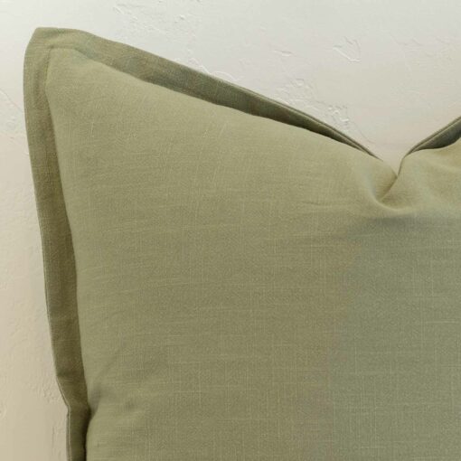 Close-up of sage linen cushion corner with subtle flange edge and soft structured finish.