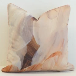 A handprinted abstract brown outdoor cushion with broad brushstrokes in brown, beige and dusty pink tones.