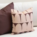 Close-up of Solterra cushion with brown abstract arch pattern on soft fabric.