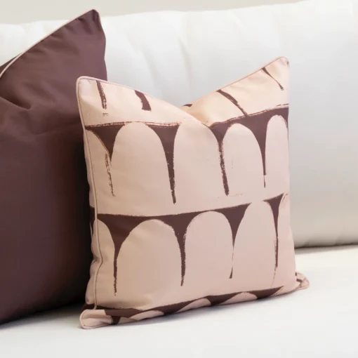 Close-up of Solterra cushion with brown arch pattern on blush background.