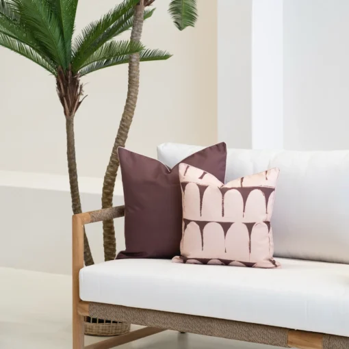 Solterra cushions styled on sofa with palm tree, featuring brown and blush patterns.