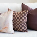 Close-up of Solterra cushions with abstract print and brown check pattern on sofa.