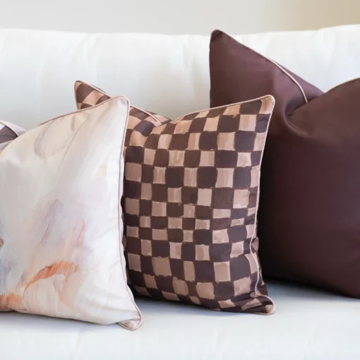 Close-up of Solterra cushions with abstract print and brown check pattern on sofa.