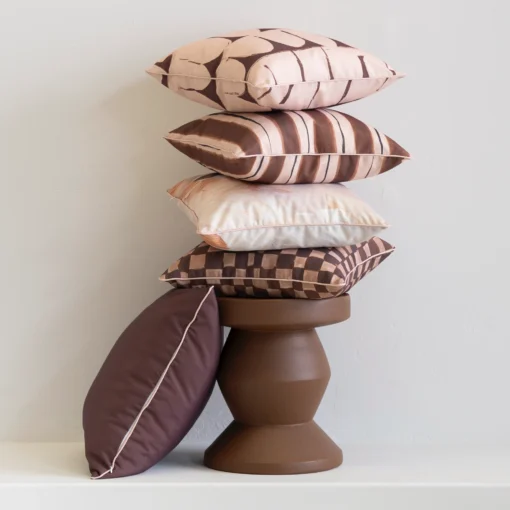 Stacked Solterra cushions in brown and blush patterns on sculptural pedestal.