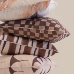 Close-up of stacked Solterra cushions with brown check, stripe and abstract patterns.