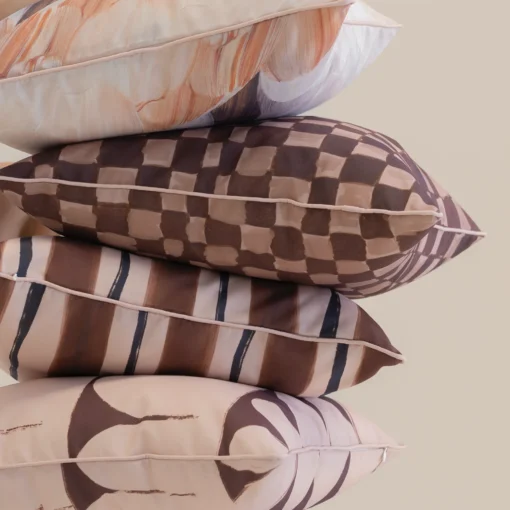Close-up of stacked Solterra cushions with brown check, stripe and abstract patterns.