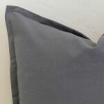 Close-up of steel blue linen cushion corner with tailored edge detail and subtle texture.