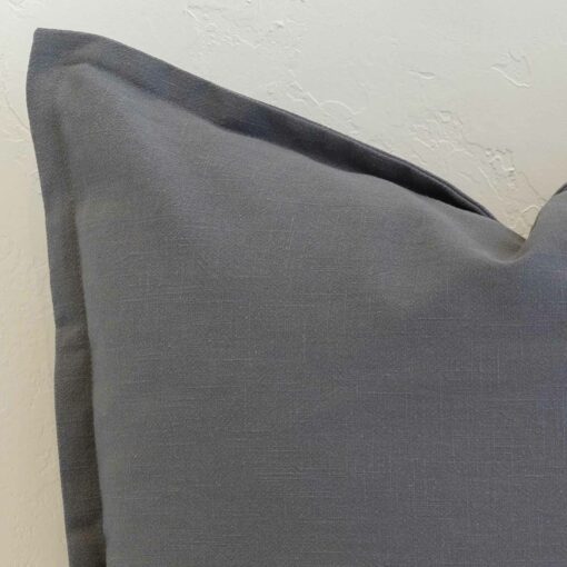 Close-up of steel blue linen cushion corner with tailored edge detail and subtle texture.